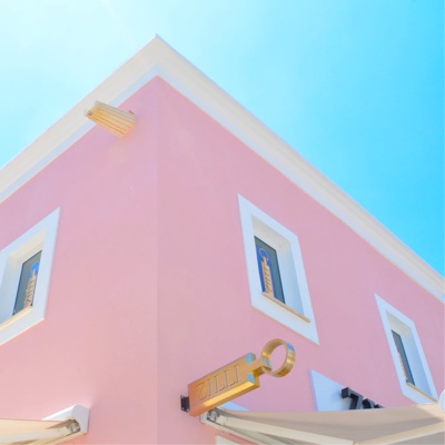 A pink building with white trim and gold signage against a clear blue sky